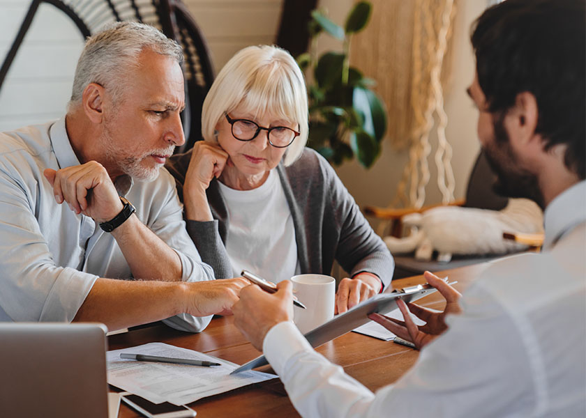 A professional explaining paperwork to elderly retired couple front of desk